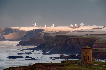 The octagonal 'Temple of the Winds' at Bude, North Cornwall, modelled on the 'Tower of the Winds' in Athens, was built by Bude's famous Acland Family in 1840 and moved to the present location in 1880. The headland is now known as 'Compass Point' after the markings of the cardinal and ordinal directions on its exterior walls. It provides a good source of foreground interest in any shot up the coast from here, though the light and drama is rarely as good as in this shot. At low tide an unbroken beach leads all the way up to the sunlit headland; behind it, and greatly foreshortened in this scene, the radar dishes of GCHQ Bude, built on the former WWII airfield of RAF Cleave, lie nearly 8km up the coast. A big Atlantic winter storm was hitting the coast, and it was this that I had gone out to photograph at dawn; I was not aware until I got there that snow had fallen in the night, and was fortunate to get the sun coming through to light it, and the radar dishes, during an all too brief break in the clouds.